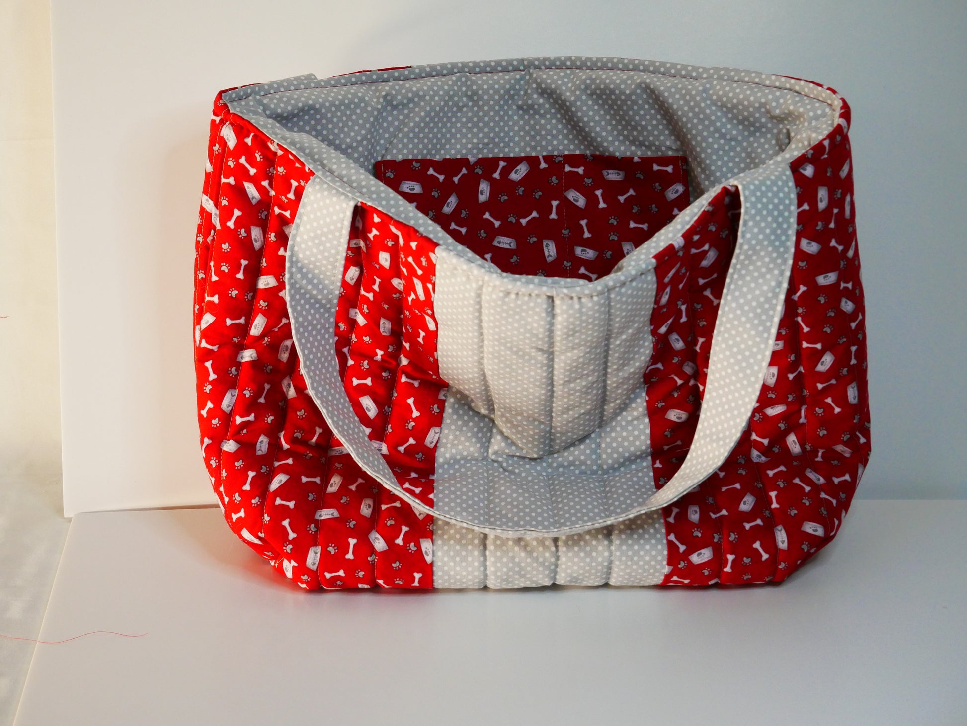 A handmade quilted red and light grey dog themed tote bag.