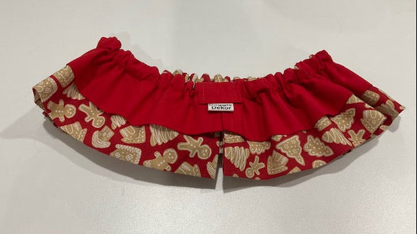 A red fabric pet collar with a ruffled edge, featuring a patterned outer trim in red and beige with gingerbread motifs - the neck ruffle by doggie dekor calgary