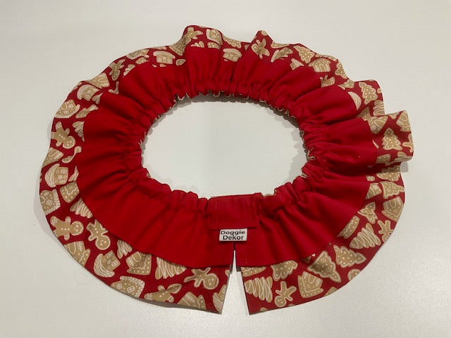 A red fabric pet collar with a ruffled edge, featuring a patterned outer trim in red and beige with gingerbread motifs - the neck ruffle by doggie dekor calgary