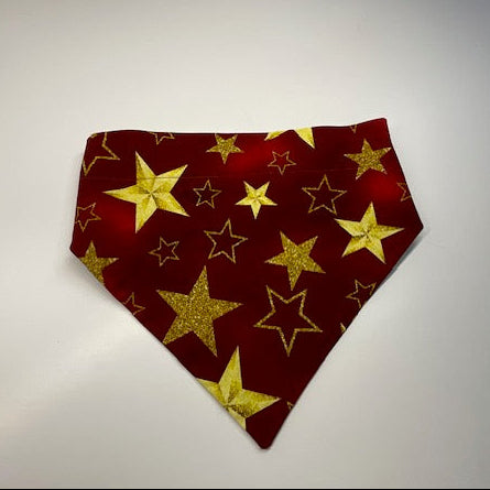 A handmade scrunchie dog bandana sewn with a fabric pattern of gold stars on a red and burgundy fabric - Doggie Dekor