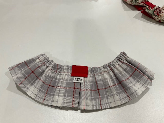 A neck ruffle by doggie dekor in a light grey plaid with red accents