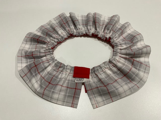 A neck ruffle by doggie dekor in a light grey plaid with red accents