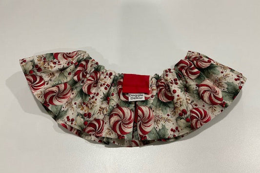 A ruffled pet collar with a festive holiday print of red and white peppermint candies, green holly leaves, and red berries - the neck ruffle by doggie dekor calgary