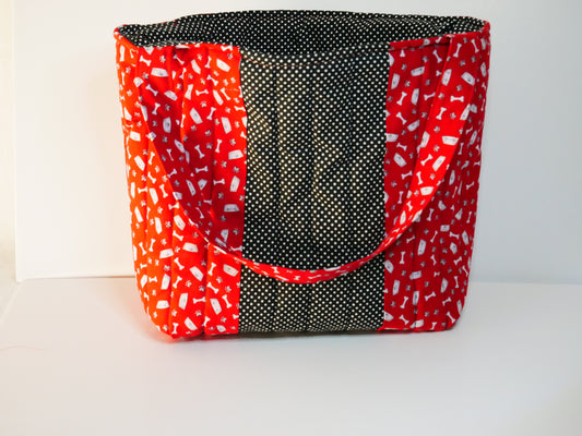 A fabric tote bag with a red and white dog themed fabric - a black and white polka dot center panel and lining.