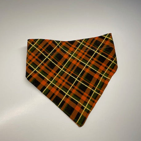 A scrunchie dog bandana with a fall inspired flannel pattern in orange, black, green and a sparkly yellow stripe.