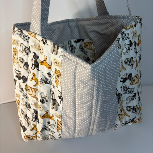 A handmade fabric tote bag with a white background, featuring printed dog patterns on the front and sides, and a gray polka-dot fabric panel on the front and handles.